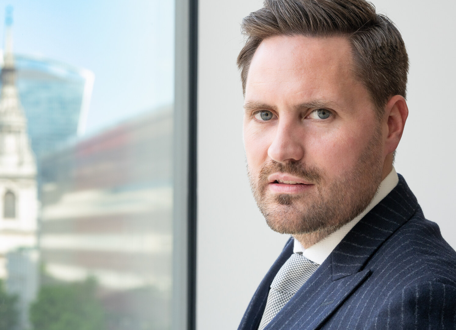 Portrait of a man in a suit, looking at the camera.