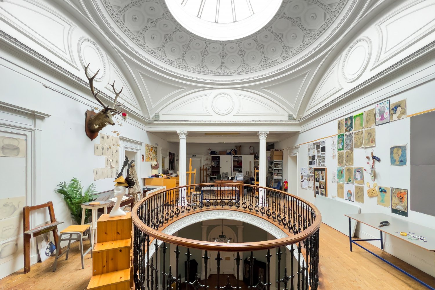 Interior view of an art studio with a circular balcony overlooking a lower level.